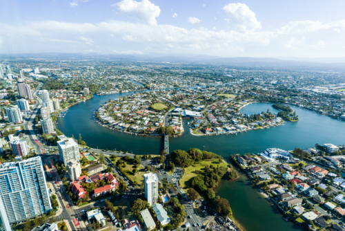 Aerial view of waterfront suburbs and canals in a sprawling coastal city under a clear blue sky. - Australian Stock Image