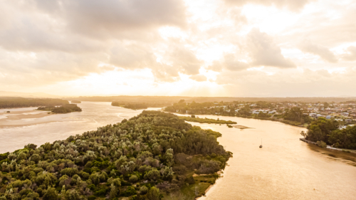 aerial view of winding river through lush green bushland at sunset - Australian Stock Image