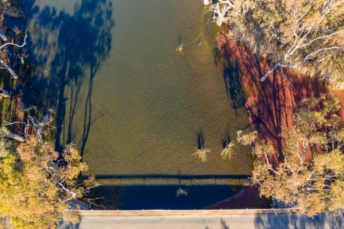 Aerial view over a bridge and river with gum trees on its banks - Australian Stock Image