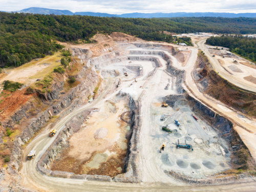 Aerial view over a quarry pit with machinery and haulage roads - Australian Stock Image