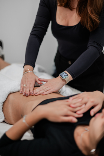 Aesthetic practitioner assessing clients abdomen while lying on a treatment bed - Australian Stock Image