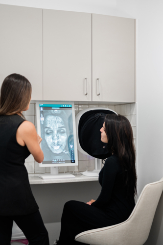 Aesthetics practitioner discussing skin analysis results during client consultation - Australian Stock Image