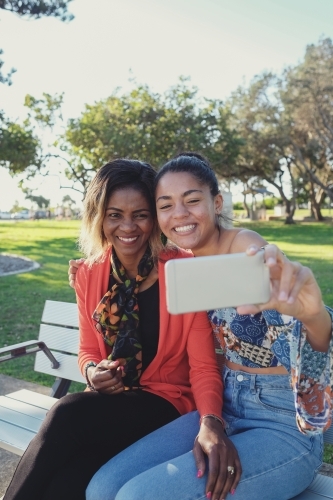 African mother and multicultural teen daughter taking selfie - Australian Stock Image
