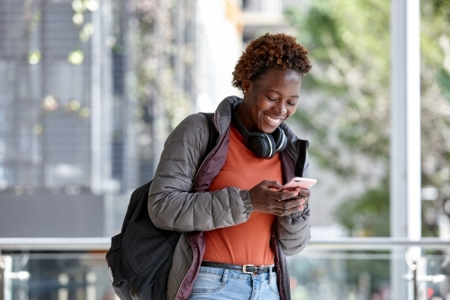 African woman having fun in city checking mobile phone - Australian Stock Image