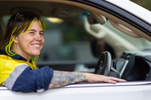 alternative-looking female tradie with bright hair highlights and nose chain in driver's seat of car - Australian Stock Image