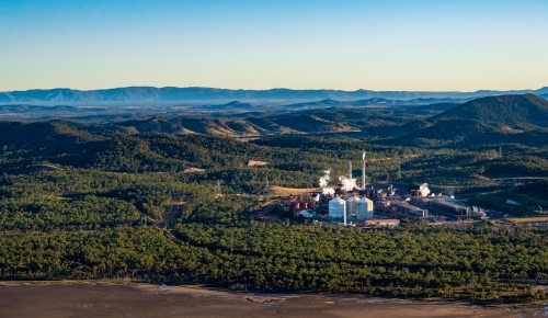 Alumina refinery with hills in the distance and mudflats in foreground, Gladstone Region, Queensland - Australian Stock Image