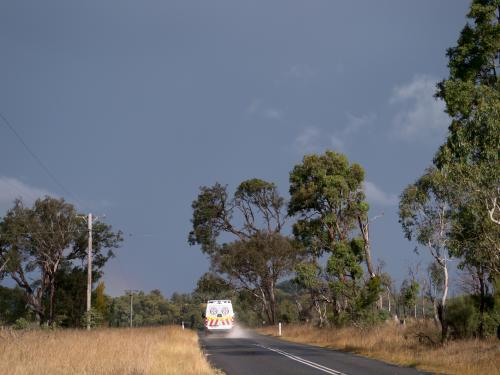Ambulance travelling away on a wet country road