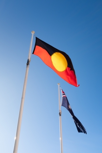 An aboriginal First Nations indigenous flag flying in front of an Australian flag - Australian Stock Image
