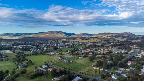 An aerial photo of a country town with green grass underneath a cloudy blue sky - Australian Stock Image