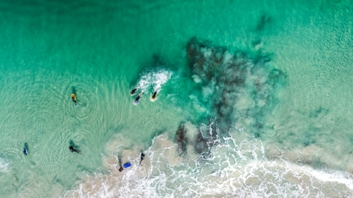 An aerial view of bodyboarders paddling for position