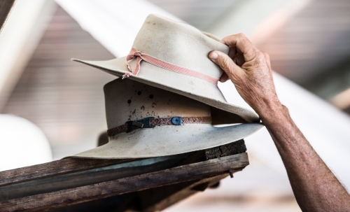 An elderly man reaches for an Akubra style hat - Australian Stock Image