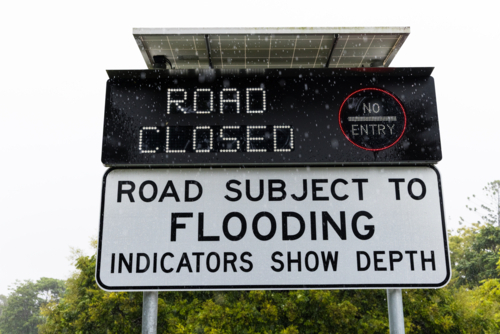 An electronic street sign in a Brisbane suburb showing a road is closed due to flooding - Australian Stock Image