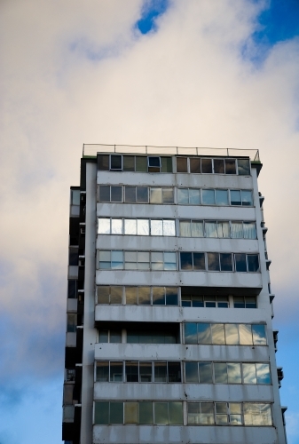 An old apartment block reflecting the cloudy sky