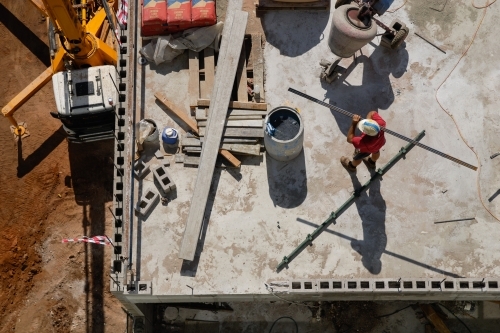 An overhead view of a construction worker carrying a beam on a building site