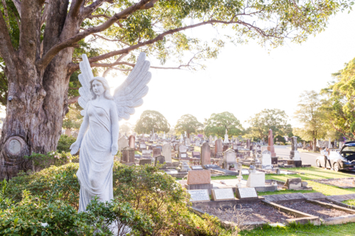 Angel sculpture and tombstones in a graveyard - Australian Stock Image