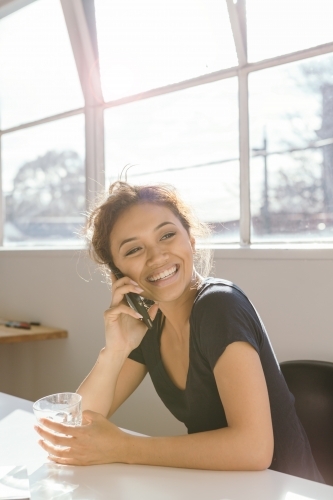 Animated young woman laughing while on the phone vertical - Australian Stock Image