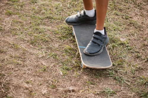 Ankle view of a child standing on a skateboard - Australian Stock Image