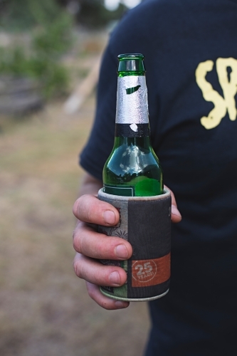 Anonymous man holding beer bottle outdoors in backyard - Australian Stock Image