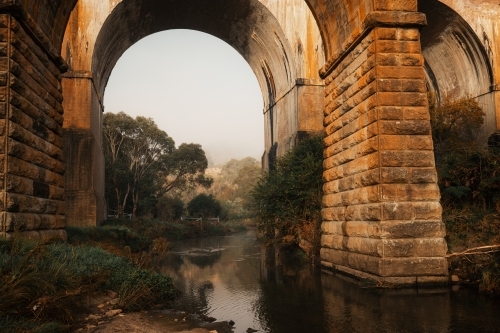 Archways of historic bridges over tranquil creek in the Blue Mountains - Australian Stock Image
