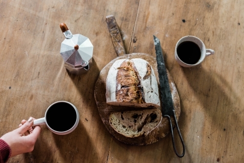 Artisan bread and stovetop espresso maker and coffee cups from above
