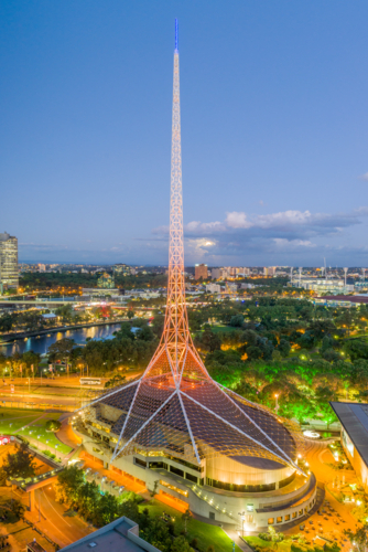 Arts Centre Melbourne illuminated at dusk with its spire glowing above the city skyline. - Australian Stock Image