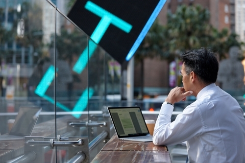 Asian businessman working on lap top in a cafe in the city - Australian Stock Image