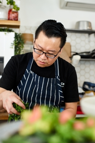 Asian chef working in kitchen at organic food cafe - Australian Stock Image