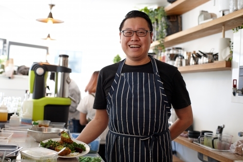 Asian chef working in kitchen at organic food cafe - Australian Stock Image