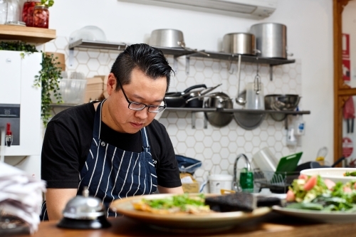 Asian chef working in kitchen at organic food cafe