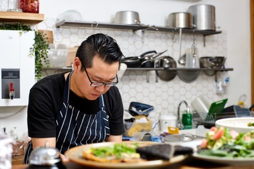 Asian chef working in kitchen at organic food cafe - Australian Stock Image