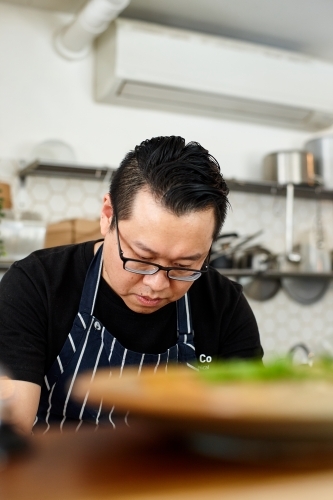 Asian chef working in kitchen at organic food cafe - Australian Stock Image