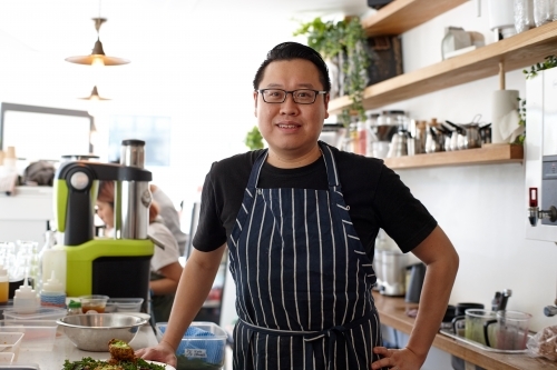 Asian chef working in kitchen at organic food cafe - Australian Stock Image