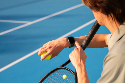 asian man checking his fitness smartwatch at tennis - Australian Stock Image