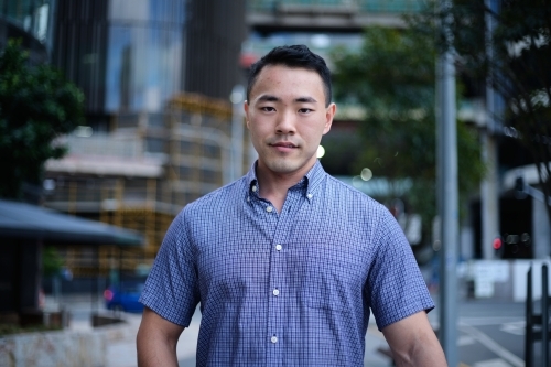 Asian man in blue shirt with city background - Australian Stock Image
