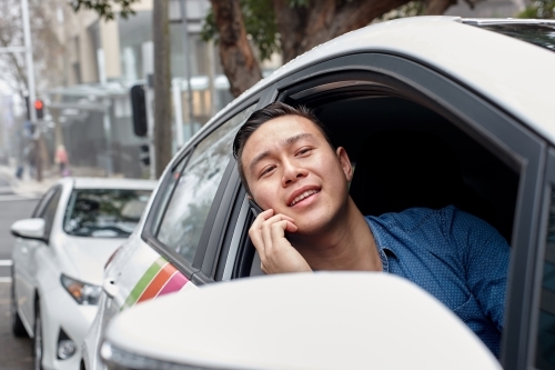 Asian man in parked vehicle looking out window