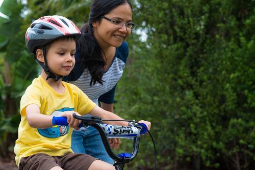 Asian mum teaching her mixed race boy to ride a bike