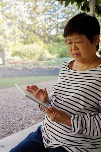 Asian senior woman using tablet - Australian Stock Image