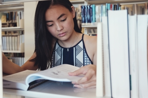 Asian student reading book in university library