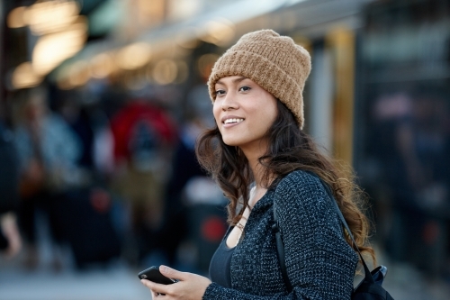 Asian woman getting off train at station with mobile phone - Australian Stock Image