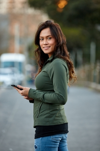 Asian woman hailing taxi with mobile phone - Australian Stock Image
