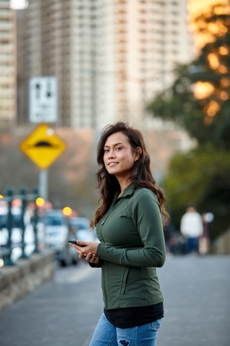 Asian woman hailing taxi with mobile phone - Australian Stock Image