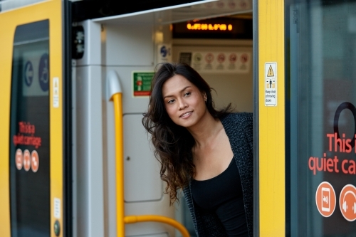 Asian woman looking out from train at station - Australian Stock Image