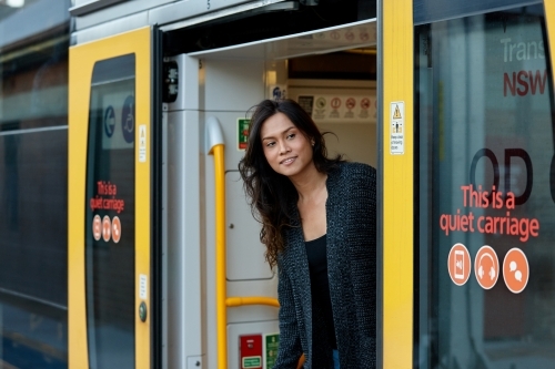 Asian woman looking outside of train at train station - Australian Stock Image