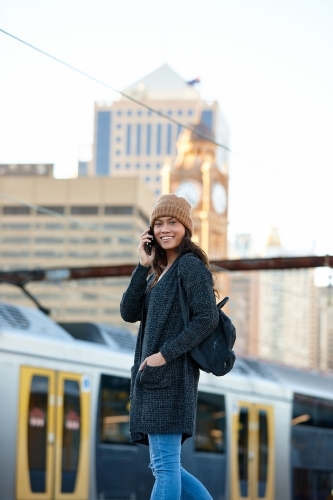 Asian woman talking on phone waiting at train station - Australian Stock Image