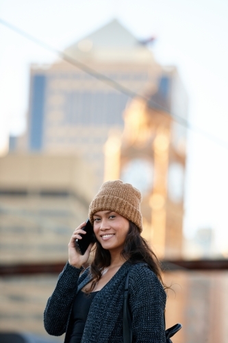 Asian woman talking on phone waiting at train station - Australian Stock Image