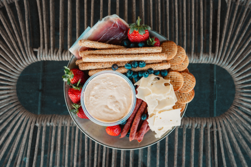 Assorted cheeses, meats, and fruits on a platter for a gourmet snack. - Australian Stock Image