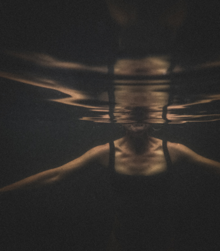 Athletic Upper female torso in black bathers underwater with reflection - Australian Stock Image