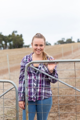 Attractive young woman at farm gate - Australian Stock Image