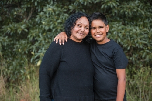 Aunty and boy smiling while standing in the bush - Australian Stock Image