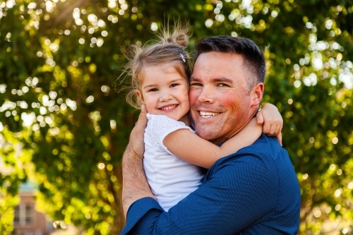 Aussie dad hugging his young daughter outside - Australian Stock Image